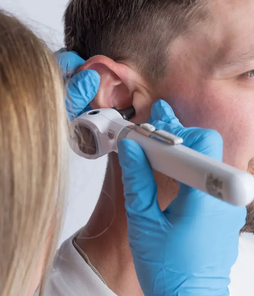Deanna examining a patient’s ear with a handheld otoscope during an ear health check